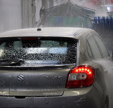 Een zilverkleurige Suzuki-auto wordt gewassen in een automatische wasstraat.