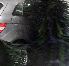 Een auto wordt gewassen in een automatische wasstraat met draaiende borstels.