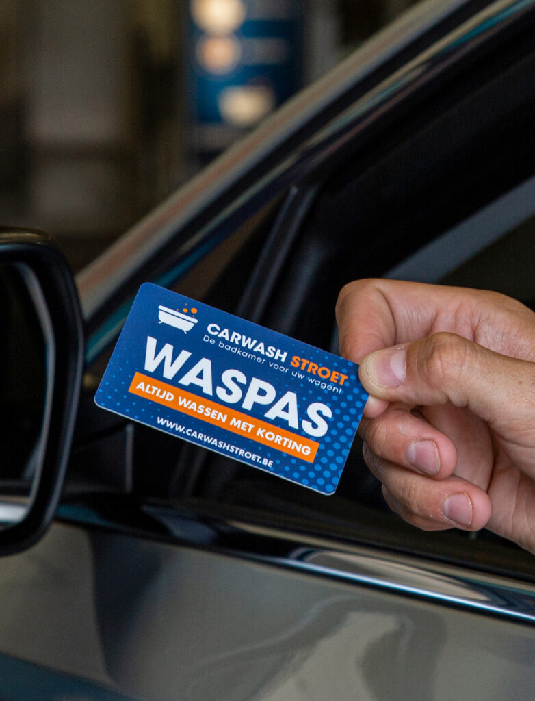 Een hand houdt een "Waspas" kaart vast voor een auto van Carwash Stroot.
